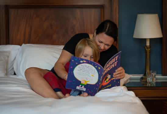 Parent and child reading a children's book together, promoting bonding and emotional well-being.